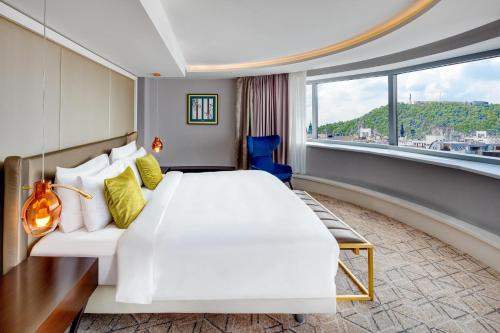 a hotel room with a large bed and a large window at Kempinski Hotel Corvinus Budapest in Budapest