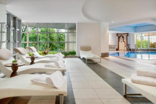a hotel lobby with a pool and white chairs at Kempinski Hotel Corvinus Budapest in Budapest