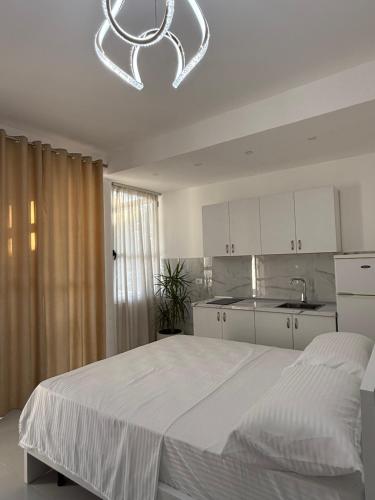 a white bedroom with a large bed and a kitchen at ELIO's Room in Durrës