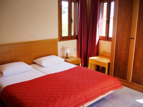 a bedroom with a bed with a red blanket at Eos Studios in Symi