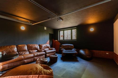 a living room with a leather couch and a chair at Willa Hamptons in Huta Podgórna
