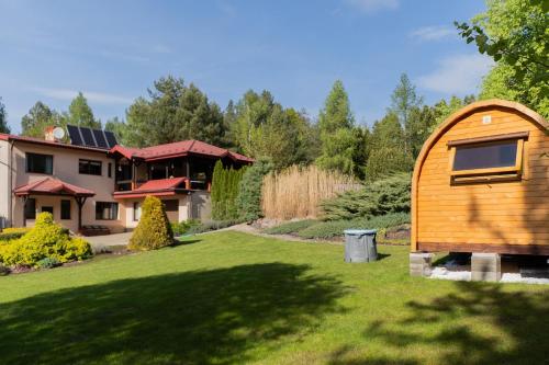 a wooden hobbit house in the yard of a house at Willa Hamptons in Huta Podgórna
