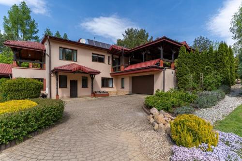 a house with a driveway in front of it at Willa Hamptons in Huta Podgórna