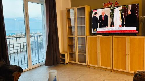 a living room with a tv and a large window at ElStefanino House in Eforie Nord