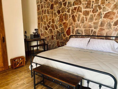 a bed in a room with a stone wall at El Callejón ORO in Real de Catorce