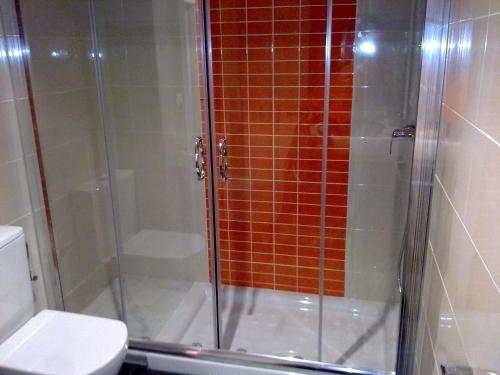 ducha con puerta de cristal junto a un aseo en Residencial Parque los Laureles, en Portonovo