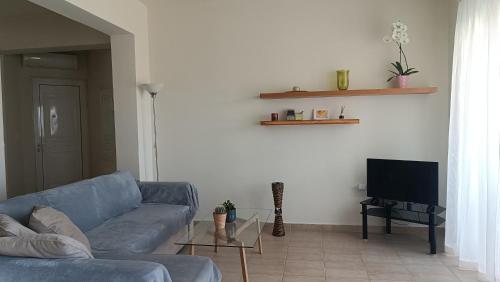 a living room with a blue couch and a tv at Relax Private Pool House in Maleme