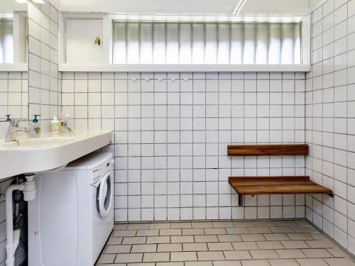 a white tiled bathroom with a sink and a washing machine at Holiday home Karrebæksminde LIII in Karrebæksminde
