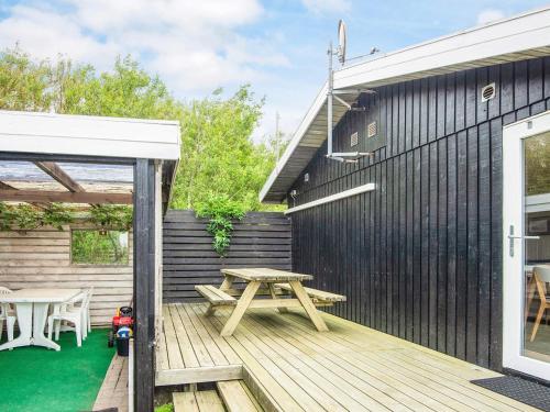 a wooden deck with a picnic table next to a black wall at 6 person holiday home in Thyholm-By Traum in Thyholm