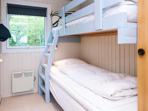 a bunk bed in a small room with a ladder at 6 person holiday home in Thyholm-By Traum in Thyholm