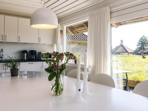 a kitchen with a table with flowers in a vase on it at 5 person holiday home on a holiday park in Karrebæksminde in Karrebæksminde