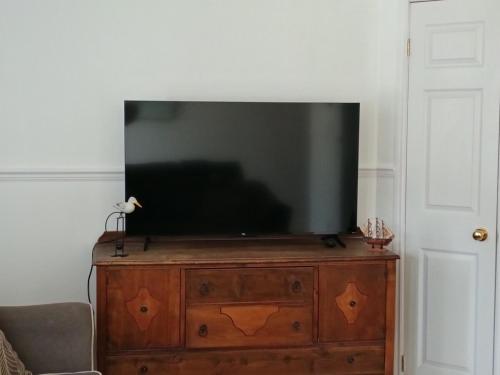 a flat screen tv sitting on top of a wooden dresser at Le Narval Hébergement Touristique in Saint-Siméon