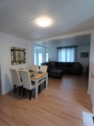 a living room with a table and chairs and a couch at Le Narval Hébergement Touristique in Saint-Siméon