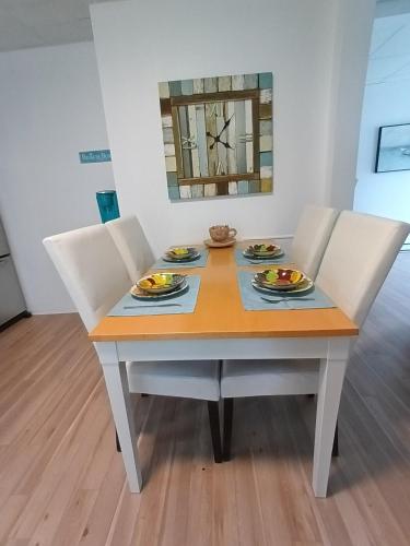 a dining room table with chairs and a table and a mirror at Le Narval Hébergement Touristique in Saint-Siméon
