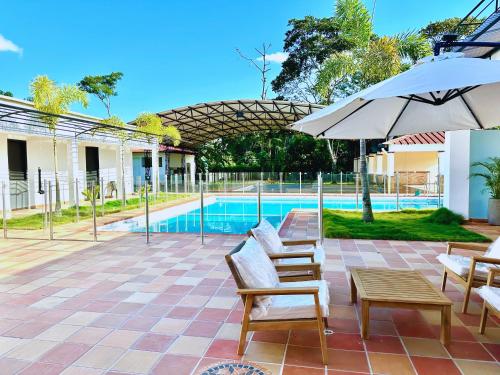 Un patio con sillas y sombrilla y una piscina. en Cofradia Lodge, en Villavicencio