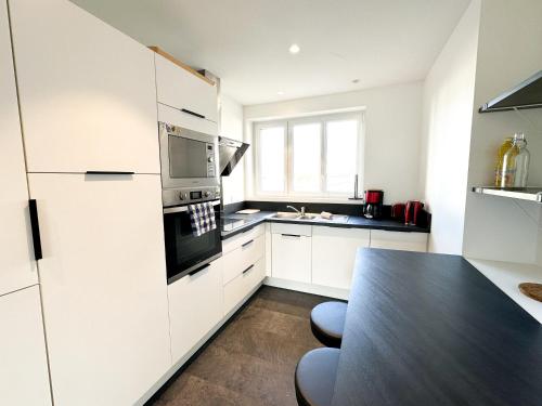 une cuisine avec des armoires blanches et un comptoir noir dans l'établissement COLIVING - WIFI - TV - Proche TRAM - L'ESCALE PARTAGEE, à Brest