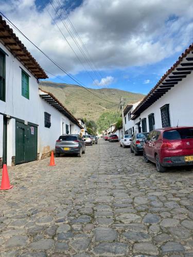 a cobblestone street with cars parked next to buildings at El Aldabón - Villa de Leyva in Villa de Leyva