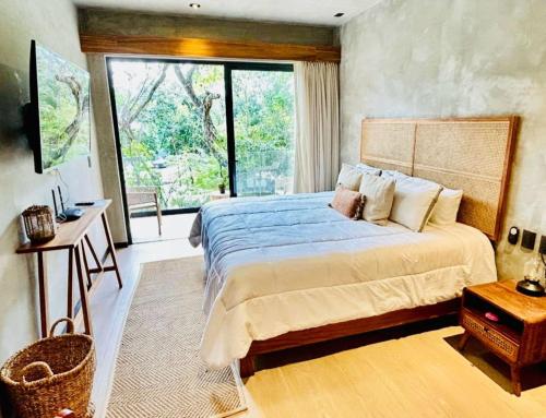 a bedroom with a bed and a large window at TUK Tulum Studios in Tulum