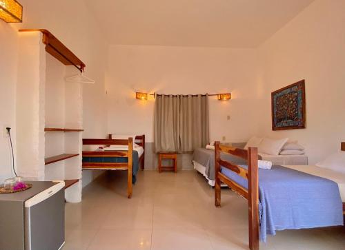 a hotel room with two beds and a desk at Pousada da Renata in Jericoacoara