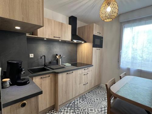 une cuisine avec des armoires en bois, une table et une fenêtre dans l'établissement Appartement Nature au calme, à Albi