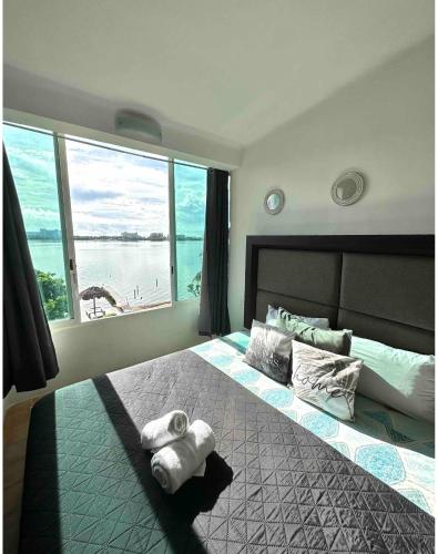 a bedroom with a large bed with a large window at Hermoso departamento en zona hotelera frente a la laguna in Cancún