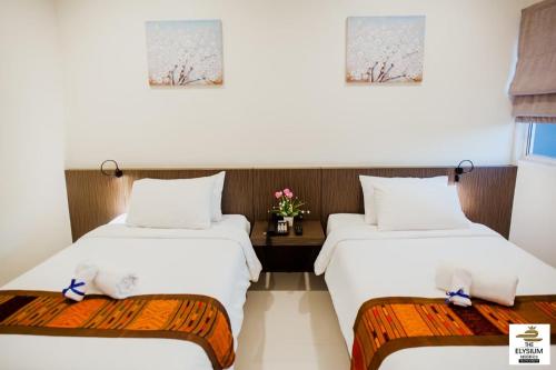 a room with two beds and a table with flowers at The Elysium Residence - SHA Extra Plus in Chalong 