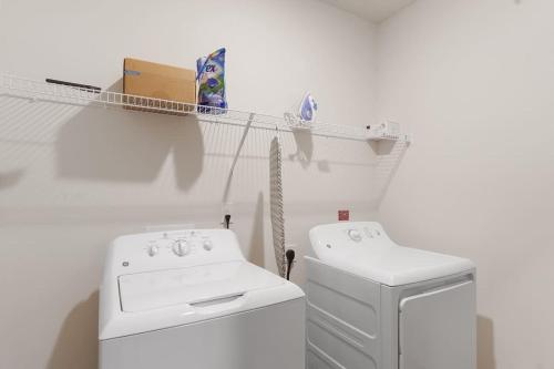 a white laundry room with a washing machine and a shelf at Luxurious King 3BR Suitein North Raleigh! in Raleigh