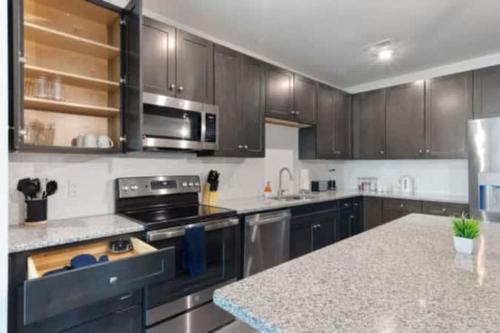a kitchen with stainless steel appliances and wooden cabinets at Luxurious King 2BR Suite in North Raleigh! in Raleigh