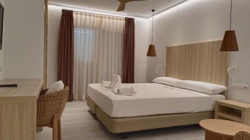 a bedroom with a bed and a table and a desk at Hotel Roca Bella in Es Pujols