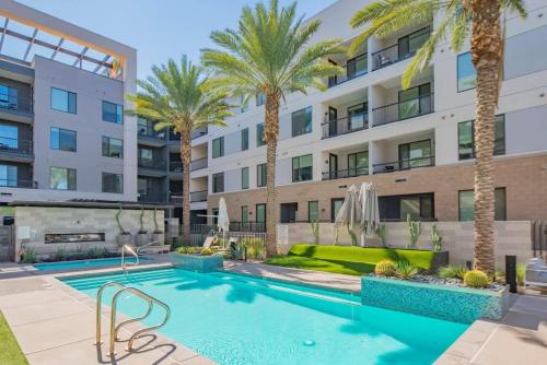 a swimming pool with palm trees in front of a building at Cozy 1BD - Pool, Gym, Parking, W-D - Sleeps 4 in Tempe