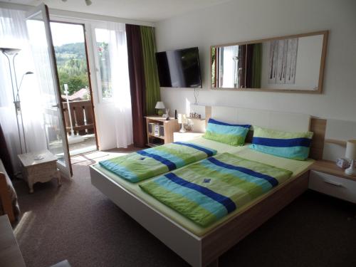 拜尔里舍艾森施泰恩Am Waldrand的一间卧室配有一张带蓝色和绿色枕头的大床