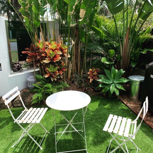 a white table and two chairs in a garden at Bayhaven Lodge in Byron Bay