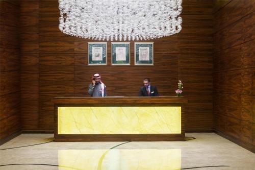 two men in suits standing at a reception desk at Kempinski Al Othman Hotel Al Khobar in Al Khobar