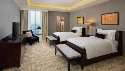 a hotel room with two beds and a television at Kempinski Al Othman Hotel Al Khobar in Al Khobar