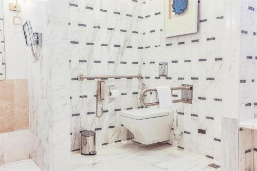 a white bathroom with a toilet and a sink at Kempinski Al Othman Hotel Al Khobar in Al Khobar