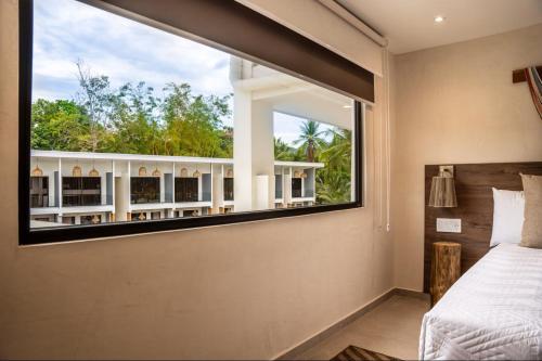 a bedroom with a window looking out at a balcony at Lia Hotel Jaco in Jacó