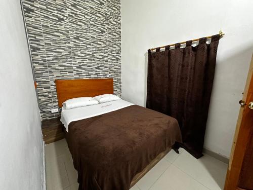 a bedroom with a bed and a brick wall at LA PLAZOLETA in Doradal