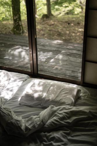 an unmade bed in front of a window at FUMI hakone 森の露天風呂 in Hakone