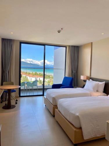 two beds in a hotel room with a view of the ocean at Oceanview Apartment at Arena Cam Ranh Resort in Thôn Hòa Ða