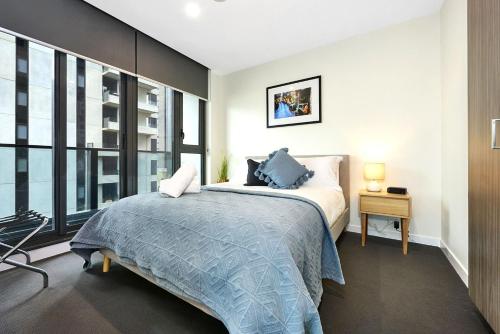 a bedroom with a bed and a large window at Spencer St Serenity Stylish Urban Escape in the CBD in Melbourne