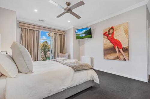 a bedroom with a white bed with a ceiling fan at Blair Street - Luxury Home with Pool and Theatre in Moama