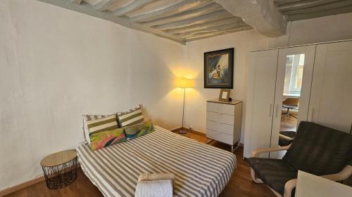 une petite chambre avec un lit et une chaise dans l'établissement Au Vieux Palais - City Center Studio, à Rouen