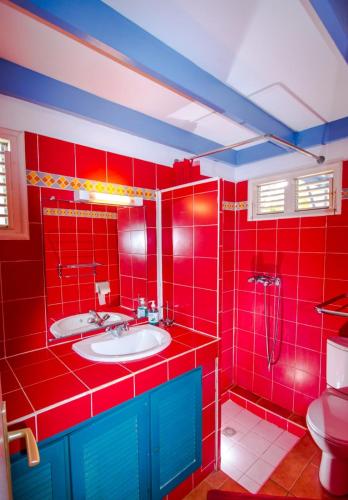 a red bathroom with a sink and a toilet at Bungalow Cocomarine in Sainte-Anne