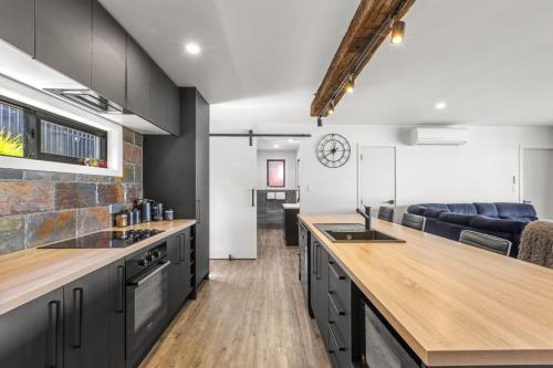 a kitchen with black cabinets and a living room at Kaitoke Retreat & Studio in Raglan