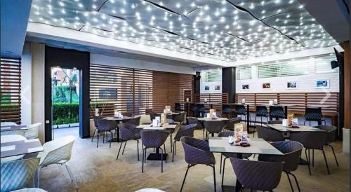 a restaurant with tables and chairs and lights on the ceiling at Premier Fort Beach Sveti Vlas in Sveti Vlas