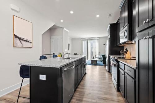 a large kitchen with black cabinets and a counter top at Luxurious King 3BR Townhouse Mins to Uptown CLT! in Charlotte