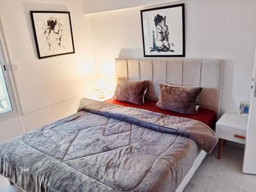 a bedroom with a large bed and two pictures on the wall at Lina in Dar Salah Bey
