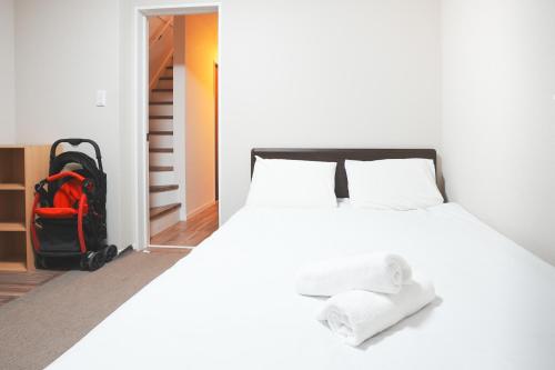 a bedroom with a large white bed with a backpack at 大阪指定特区民泊小田別荘天王寺店OdaVillaTennoji in Osaka