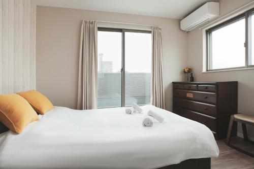 a bedroom with a large white bed and a window at 大阪指定特区民泊小田別荘天王寺店OdaVillaTennoji in Osaka