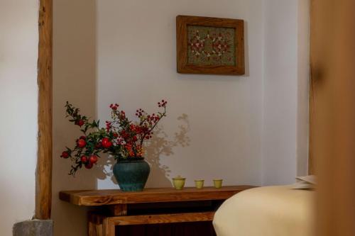 a vase with flowers on a table with two glasses at Lijiang half yard hotel in Lijiang